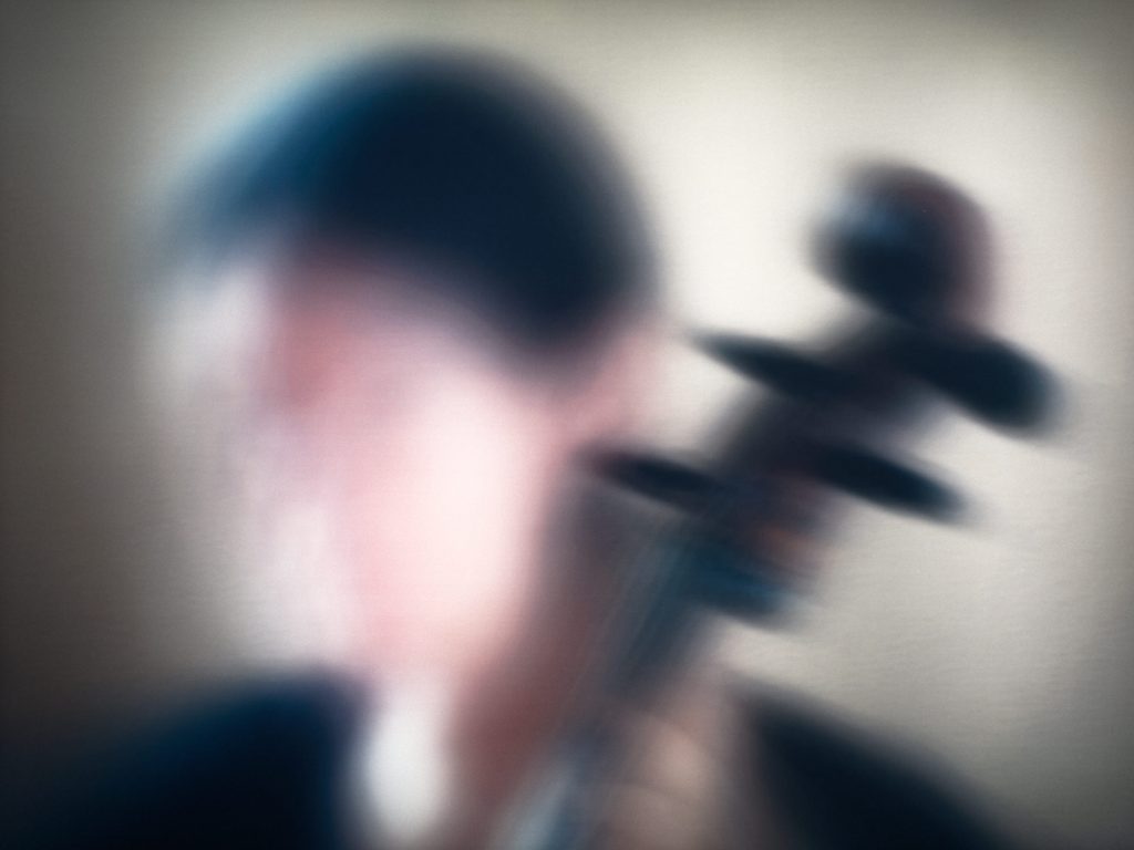 Fotografía de la obra “Bach's Suite for Cello #2” de Jim Campbell, una imagen borrosa que sugiere la figura de un músico con violonchelo.
